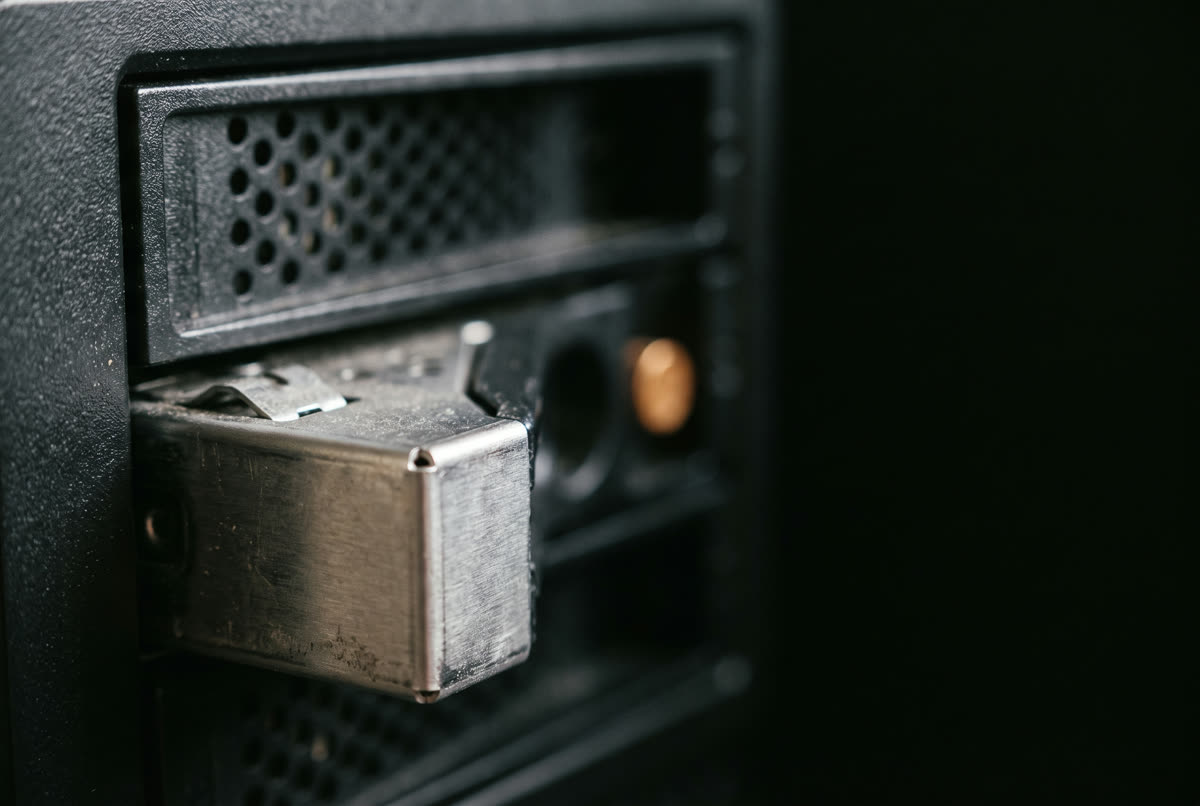 Close-up of a drive tray sliding into a bay of a personal cloud storage NAS, with the amber status light lit.